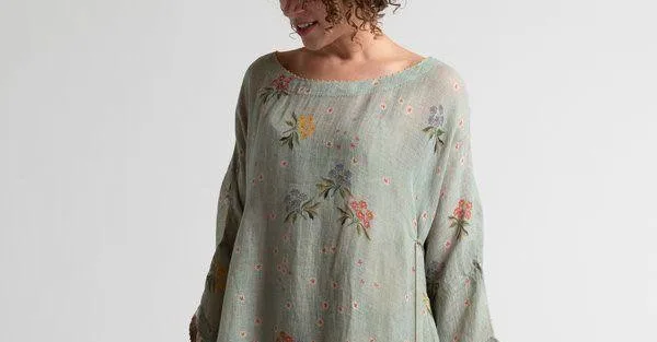 Woman in a loose sage-green floral tunic with wide sleeves, relaxed silhouette suggesting easy confident dressing