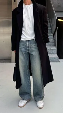Full-length look with long dark overcoat, white tee, wide-leg jeans, and sneakers, illustrating elevated relaxed basics