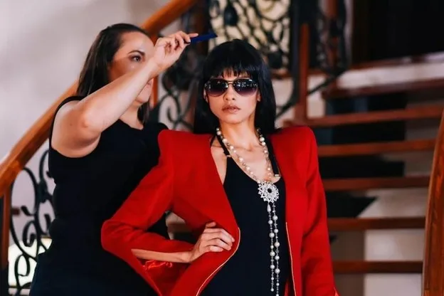 Stylist adjusting a model's hair during a session, red blazer and statement jewellery, illustrating hands-on personal styling