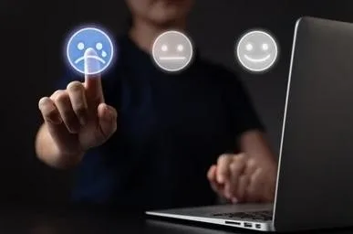 Person selecting a sad-face satisfaction icon in front of a laptop, suggesting a disappointing online shopping experience