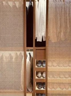 Modern walk-in wardrobe with mesh sliding doors, neatly hung clothes, and organized shoe shelves