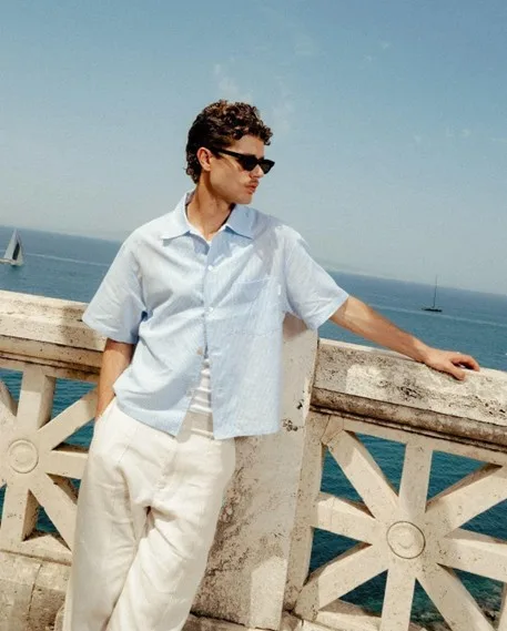 Smart-casual outfit with striped shirt and light trousers in a bright outdoor setting, relaxed professional style