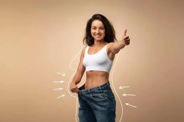 Woman showing oversized jeans after weight loss, illustrating clothes that no longer fit before a phased wardrobe rebuild