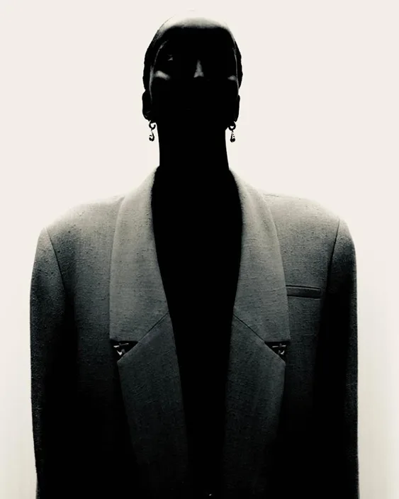 Person in a structured blazer, face in shadow, conveying authority and outfit-driven confidence